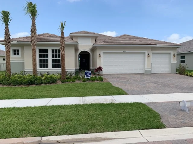 Boynton Beach single-story home with palm trees and a paver driveway