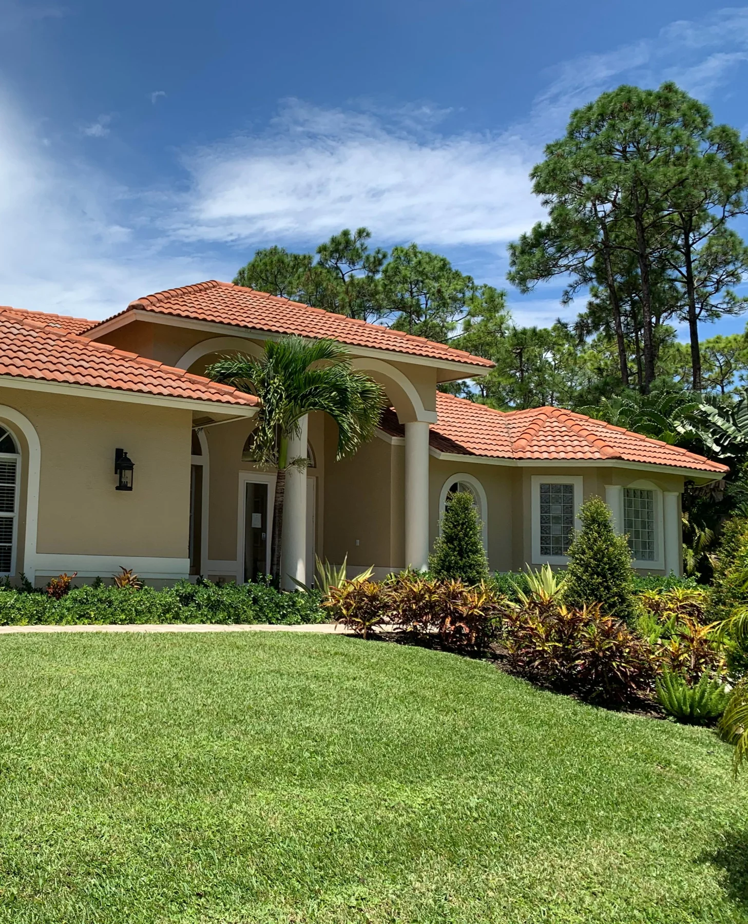 Loxahatchee home with a tile roof, covered entry and landscaped lawn